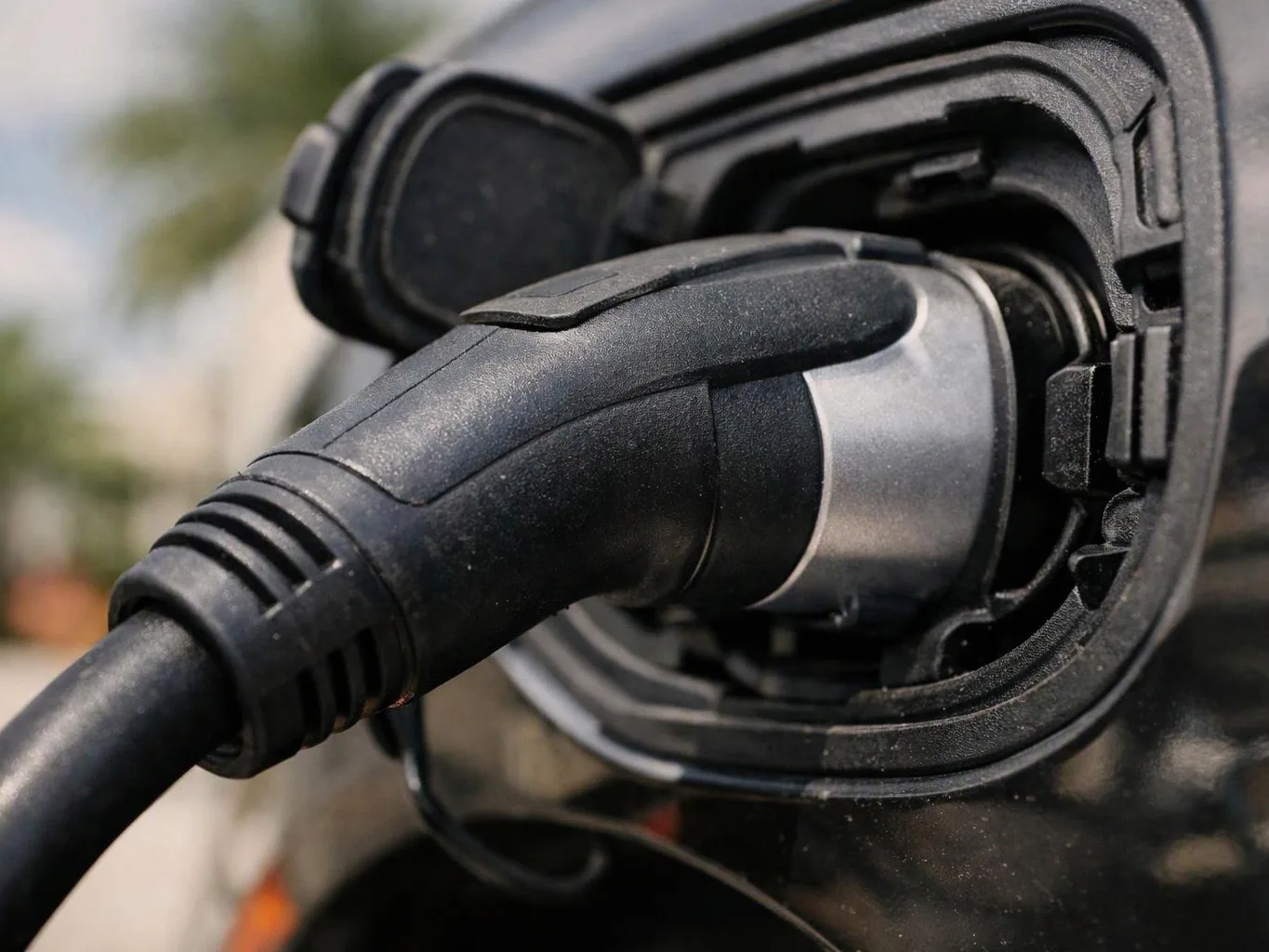 A close-up shows a charging plug connected to an electric vehicle socket